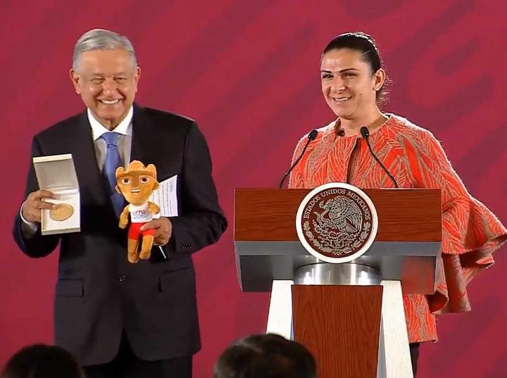 El presidente Andrés Manuel López Obrador tras recibir una medalla conmemorativa y un peluche de los Panamericanos de Perú, por parte de la titular de la CONADE, Ana Gabriela Guevara. Imagen: Captura de video
